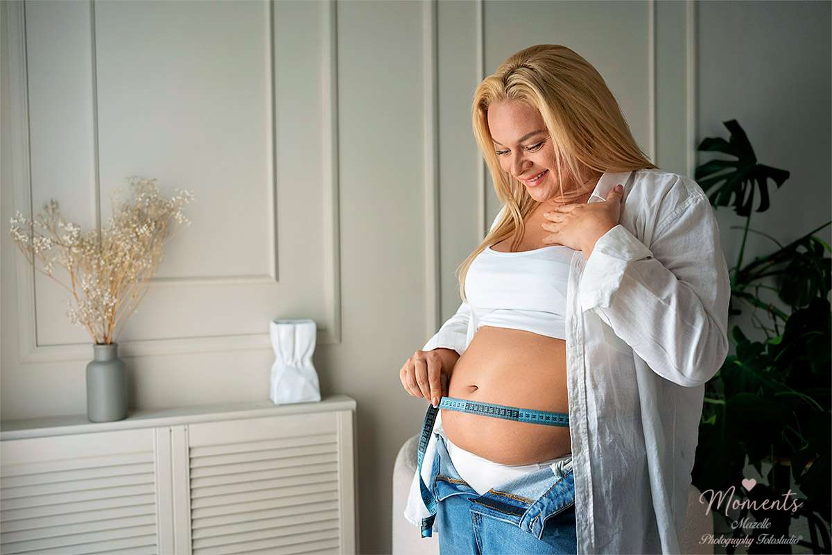 Eine schwangere Frau misst ihren Bauchumfang mit einem Metermaß – ein authentisches Motiv der Babybauch- und Schwangerschaftsfotografie von Mazelle Photography Fotostudio® auf Moments.mazelle.de. Das Bild vereint Natürlichkeit, Eleganz und Emotion und zeigt die besondere Lebensphase werdender Mütter mit künstlerischer Tiefe