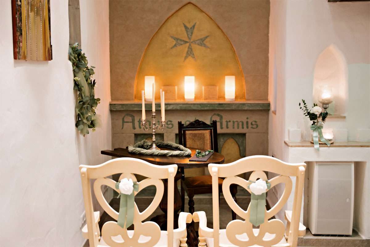 In der festlich geschmückten Ordenskapelle Binz stehen die beiden Stühle bereit, auf denen das Brautpaar während der Trauung vor dem Altar Platz nimmt. Diese liebevoll arrangierte Szene unterstreicht die besondere Atmosphäre der Zeremonie und verleiht den Hochzeitsfotos eine authentische und emotionale Note. Der hochzeitsfotograf des mazelle photography fotostudio® aus dranske auf rügen hält diesen Moment stilvoll fest und schafft Erinnerungen voller Eleganz und Bedeutung.